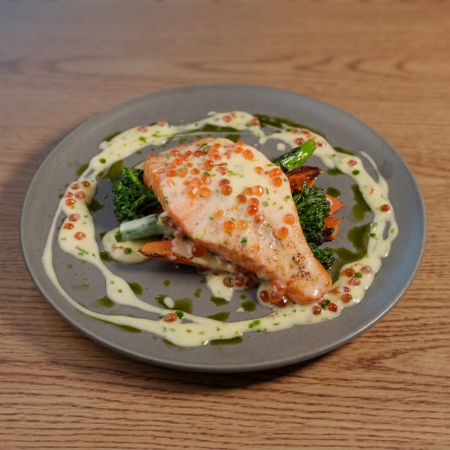 Salmon steak with creamy sauce, red caviar, broccolini and carrots.